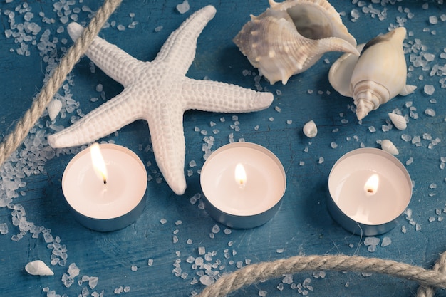 Three burning candles, starfish and shells.