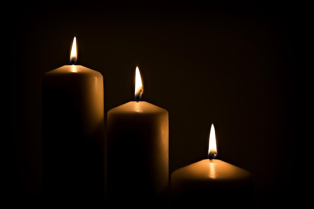 Three candles burning brightly in the dark