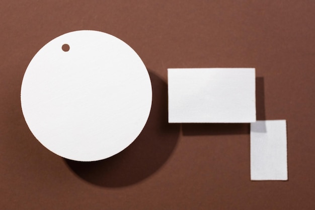 Three cardboard white colored brand blank tags of different shapes with circle on left and two rectangles on right put on brown background Tag mock up Copy space