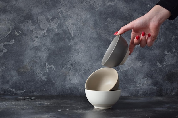 Three ceramic bowls isolated on gray background in the hand of a young girl