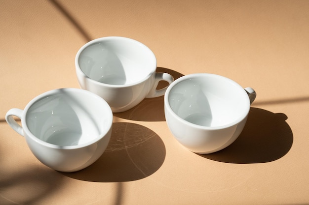 Three ceramic cups on beige studio background