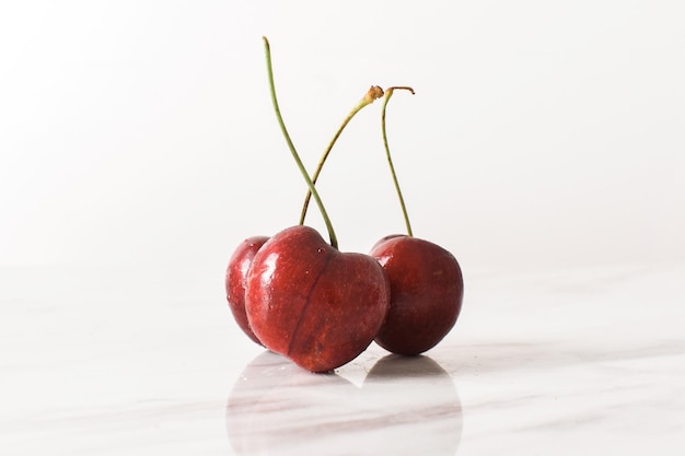 Three Cherries On White Marble Table