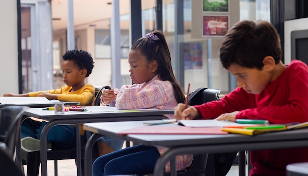 Photo three children are focused on writing at desks in a school classroom setting