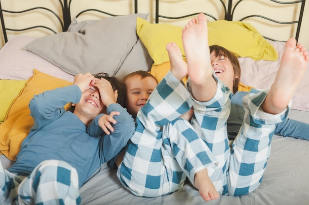 Premium Photo Three children are playing on a bed with blue and white plaid pajamas