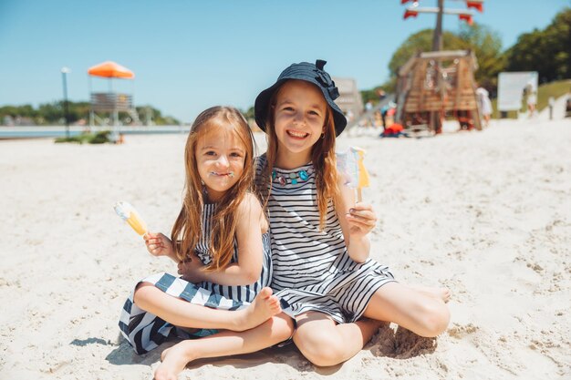 3人の子供がビーチでアイスクリームを食べるダウン症の子供は普通の生活を送っています