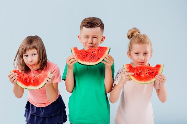 スイカのスライスを食べる3人の子供