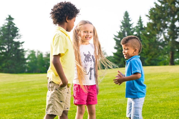 Three children have exciting conversation on the sunny glade