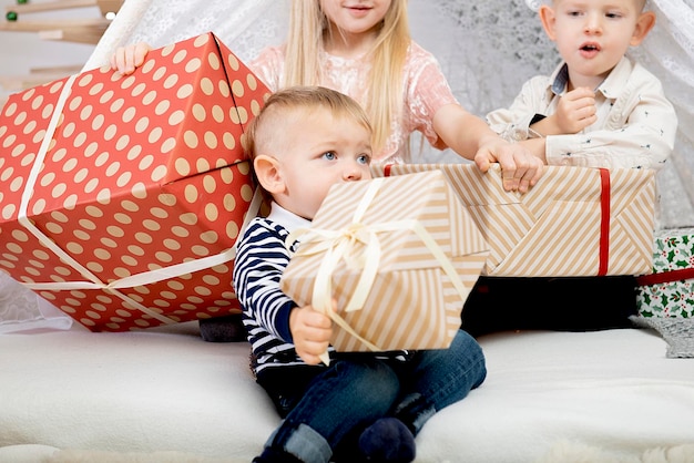 装飾された家でクリスマスギフトボックスを持った3人の子供