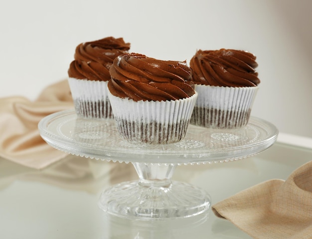 Three chocolate cupcakes on light glass background close up