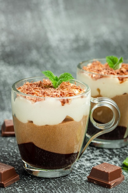 Foto tre cioccolati in un barattolo di vetro decorato con menta su uno sfondo scuro luogo di immagine verticale del delizioso dessert a strati per il testo