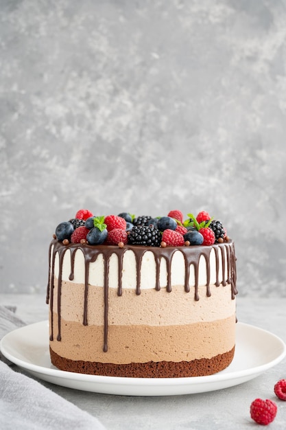 Three chocolate mousse cake with chocolate glaze and berries Cake with different taste