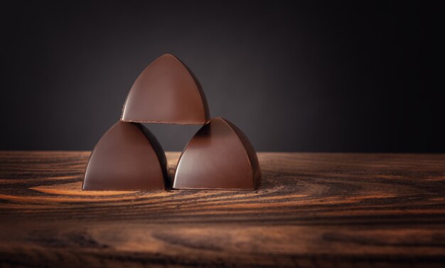 Three chocolates piled on a wooden surface,