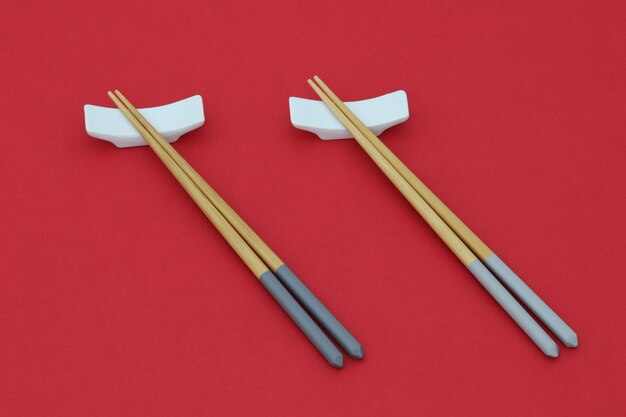 Three chopsticks with a pair of chopsticks on a red background.