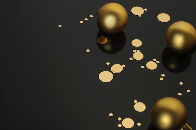 Photo three christmas balls and golden confetti on a black background