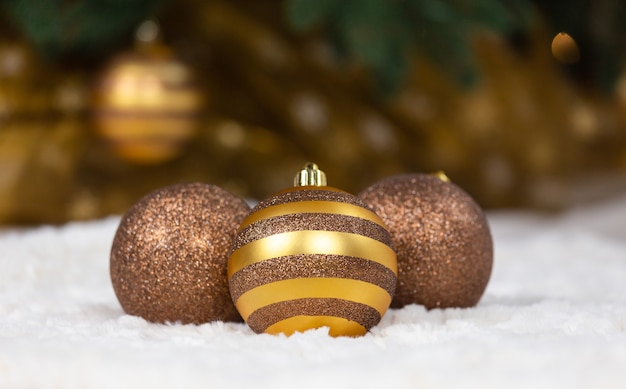 Three Christmas golden balls lie on a white plaid