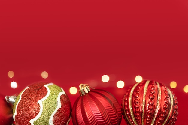 Photo three christmas red baubles design in a red background with yellow lights bokeh