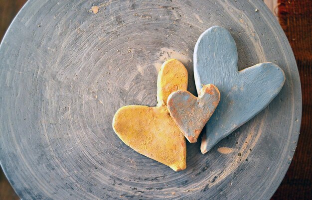 Three clay hearts painted with paints on a potter's wheel top view.