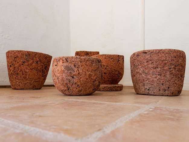 Three clay pots on the floor with a white wall in the background