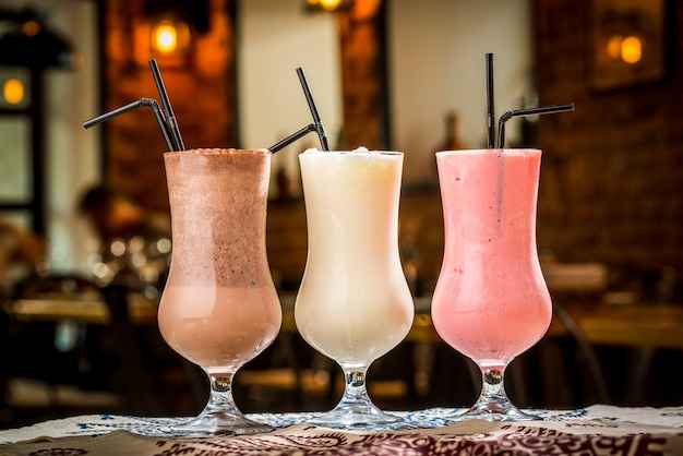 Three cocktails in plastic cups with straws