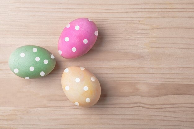 Three color easter dotted eggs on wooden table mock-up, top view with left side