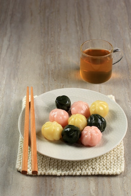 白いお皿と木の皿に3色のソンピョンクルトオク（はちみつ入り餅）。ソンピョンは元日または韓国の感謝祭の日に食べられる韓国の伝統的な食べ物です。