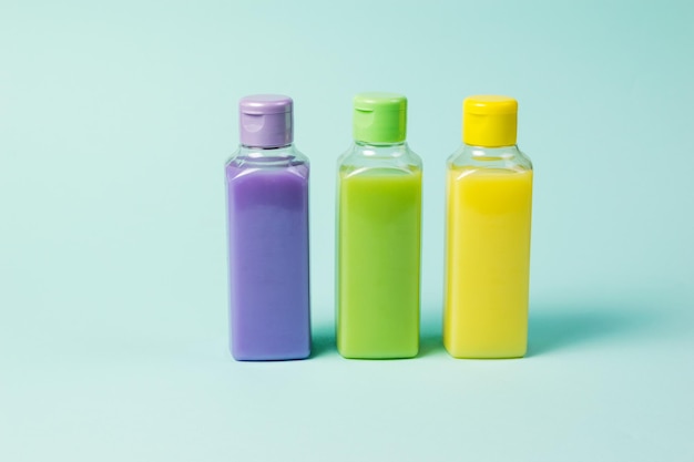 Three colored plastic bottles on a light blue background