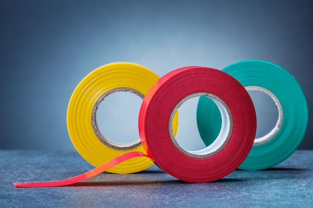 Three colored rolls of insulation tape on gray background