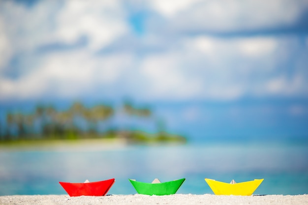 three colorful paper boats on turquoise ocean. 