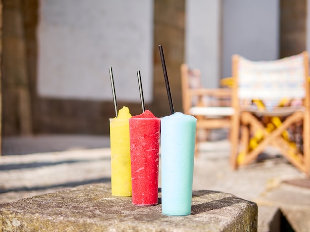 Three colorful slush drinks on a table made of stone