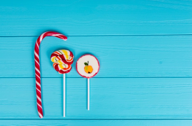 Photo three colorful sugar lollipops on wooden turquoise table