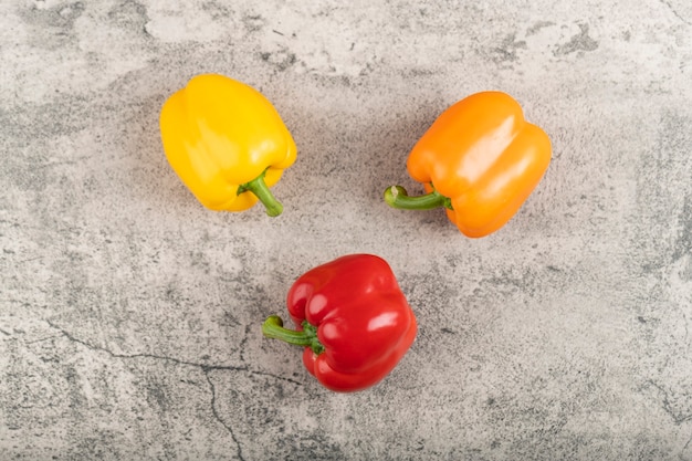 Three colorful sweet bell peppers on stone surface