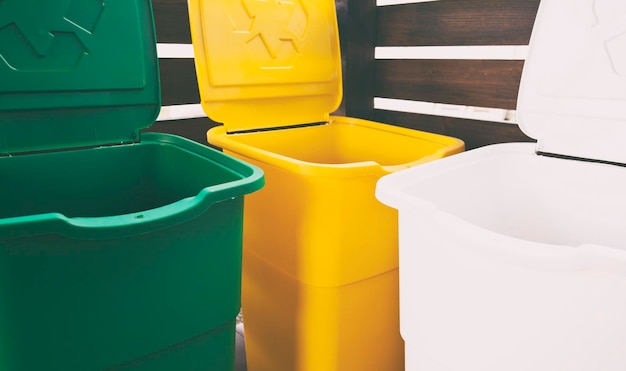 Foto tre coloratissimi bidoni della spazzatura per lo smistamento dei rifiuti per plastica, vetro e carta