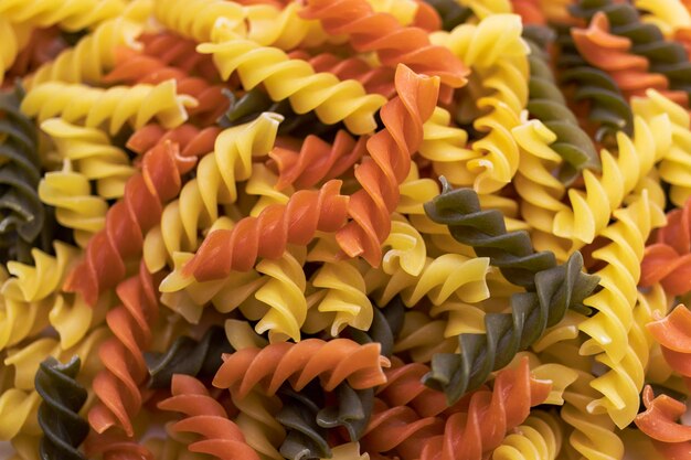 Three Colors Pasta made from durum wheat Pasta fusilli tricolor background Abstract texture of colorful pasta pattern of macaroni Bright multicolor food backdrop Uncooked colored noodles