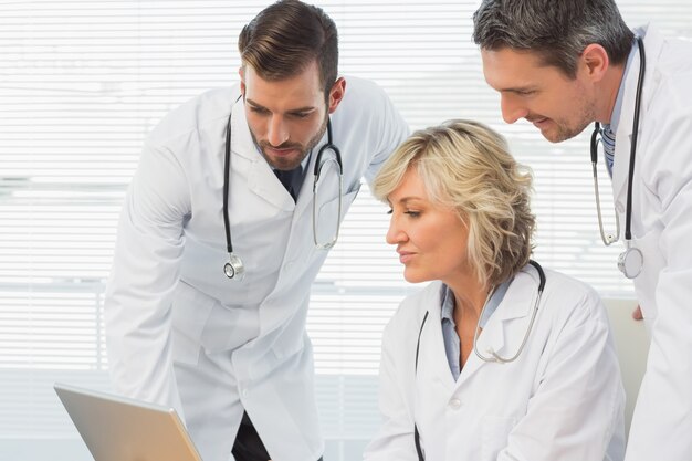 Three concentrated doctors using laptop together