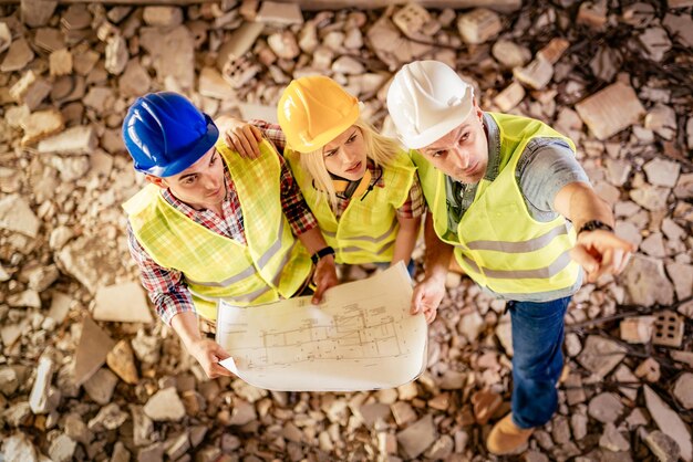 Three construction architects review plan in building damaged in the disaster.