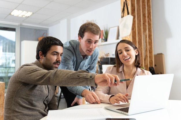 Three coworkers discussing and looking to a laptop