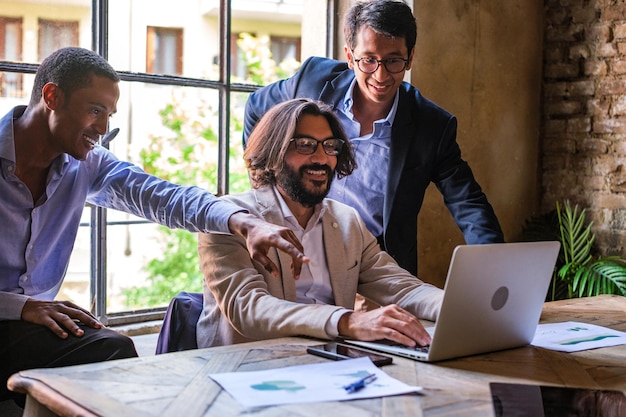 Three coworkers together in front of the computer doing\
teamwork at the meeting