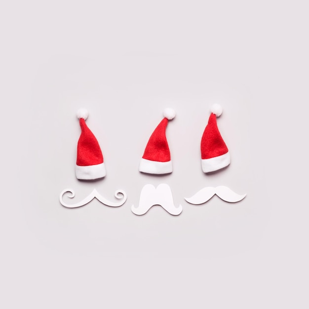 Three creative santa claus portrait of paper mustache and hats minimal christmas concept