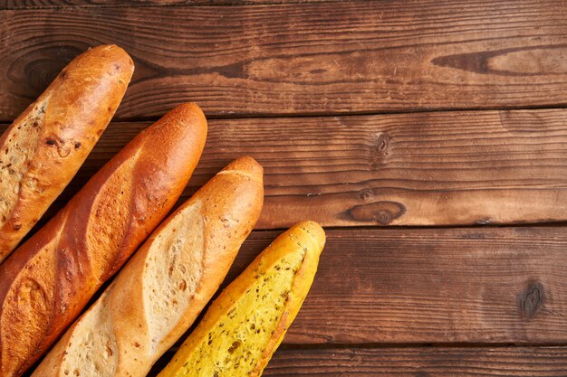 Three crispy french baguettes lie on an old wooden table with free space