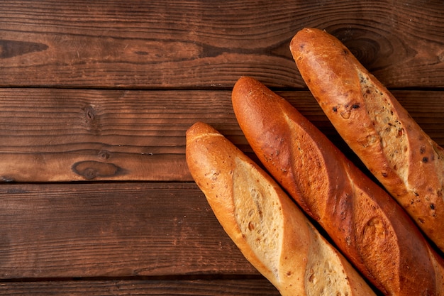 Three crispy french baguettes lie on an old wooden table