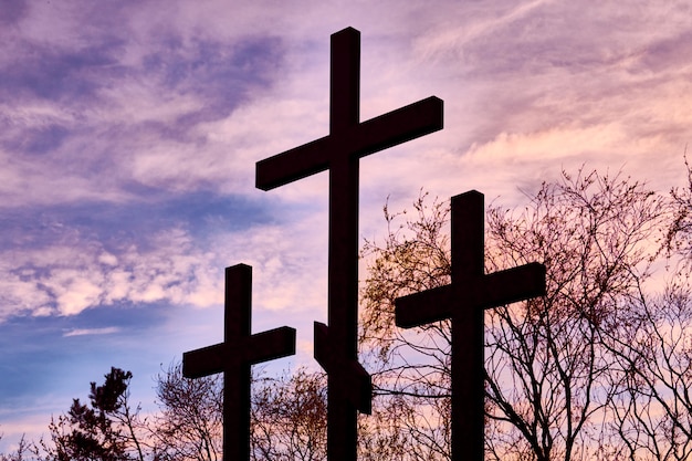 Three crosses in silhouette at sunset, dramatic sky background. Inspiring religious photo for Easter or Christian beliefs