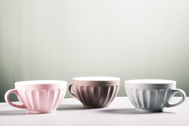 Photo three cute empty ceramic coffee cups  in a row pastel colors