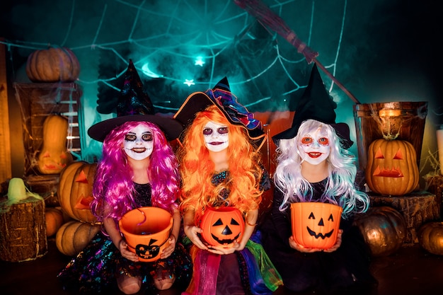 Three cute funny sisters celebrate the holiday. Jolly children in carnival costumes ready for Halloween.