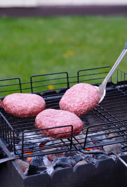 three cutlets are fried on the grill they are turned over with a metal spatula in the backyard