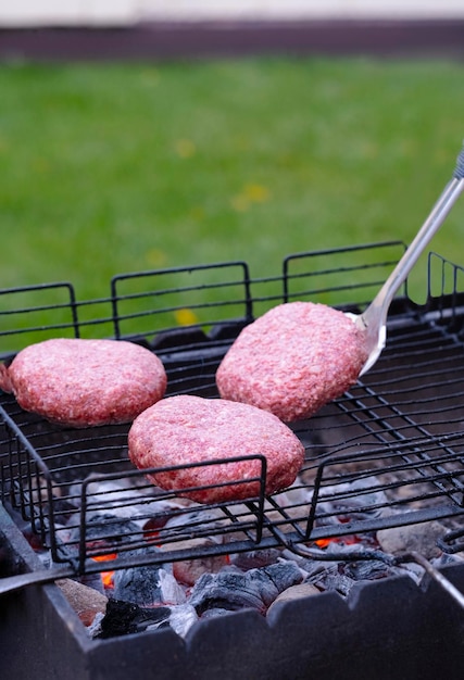 Photo three cutlets are fried on the grill they are turned over with a metal spatula in the backyard