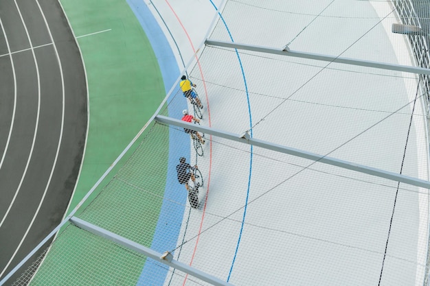 Three cyclists train on the velodrome top view Professional cyclists ride on the bike path top view