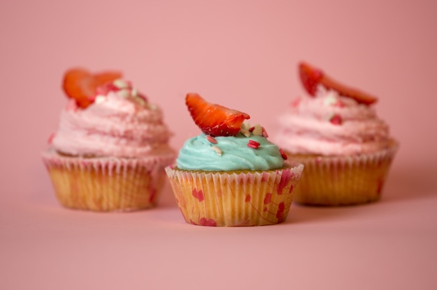 Three decorated cupcakes with blue and pink buttercream