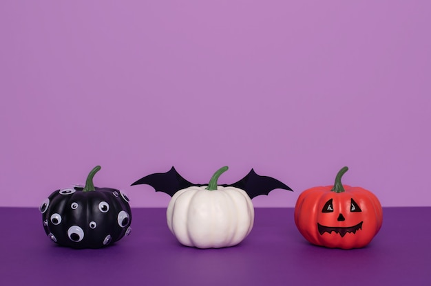 Three decorated halloween pumpkins on violet background