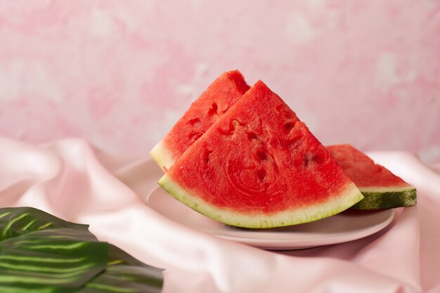 Three delicious pieces of watermelon on a pink plate