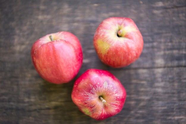 three delicious red apples on a wooden table